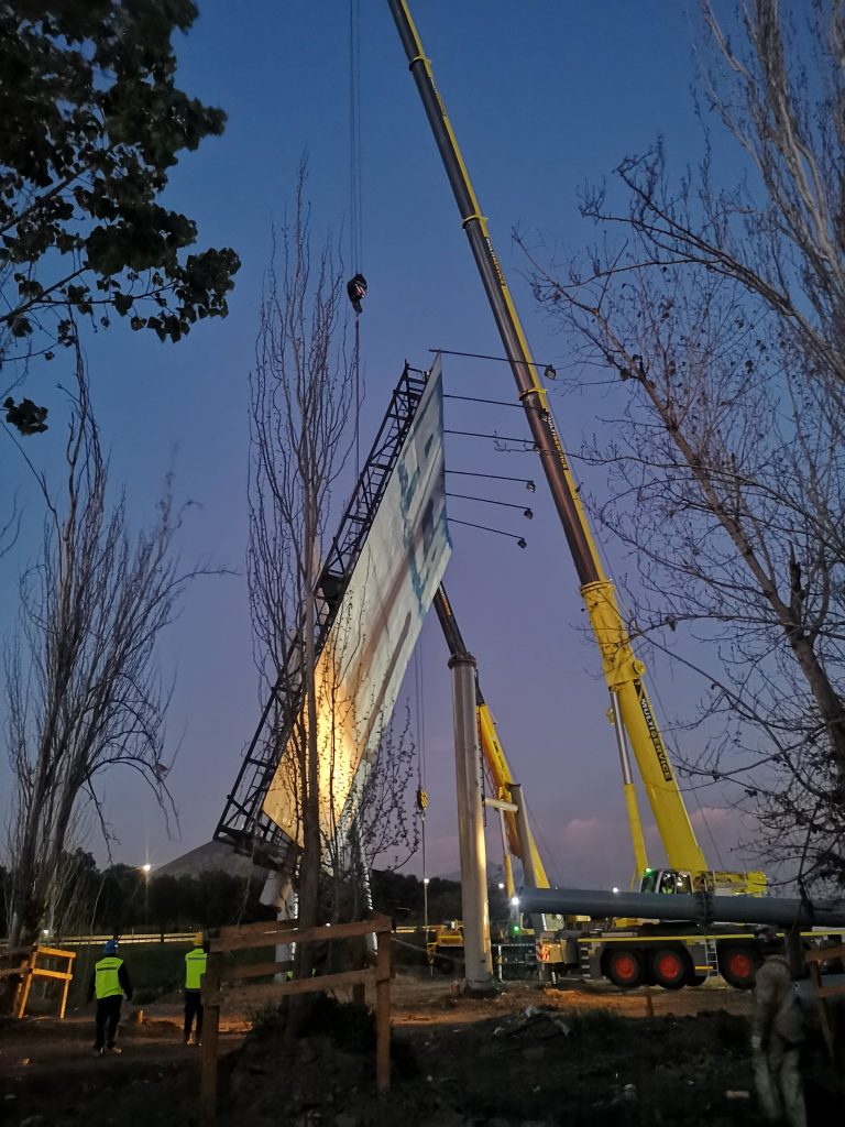 Trabajo nocturno con grúa en obra de infraestructura, BDMAG